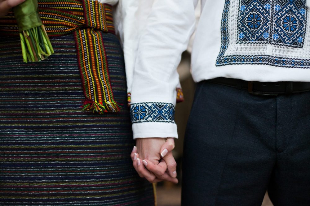 Ukrainian bride and groom in native embroidery holding hands, tr